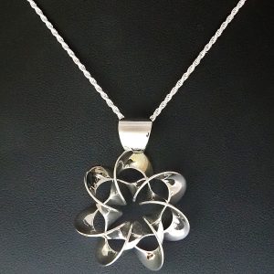 A flower-like polished silver pendant on a silver chain
